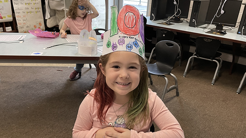 A kindergarten student shows her 100th day hat.