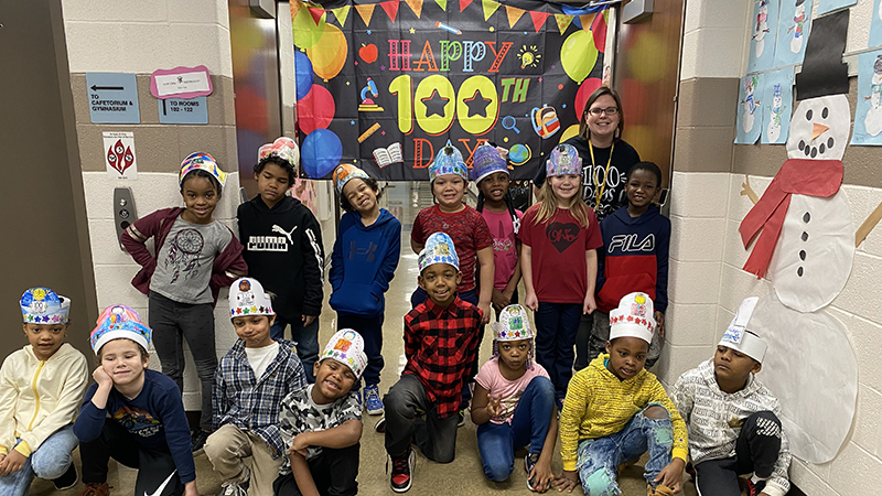 Mrs. Line's first grade class stand in front of the 'Happy 100th Day' banner.