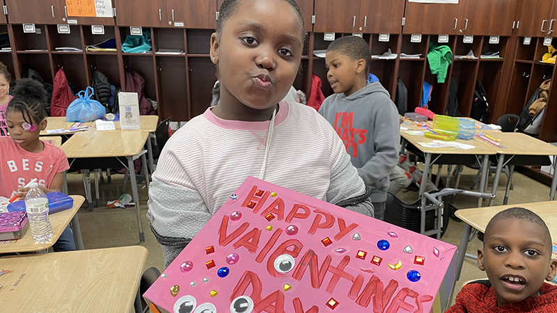 A second grader showing her Valentine box. her