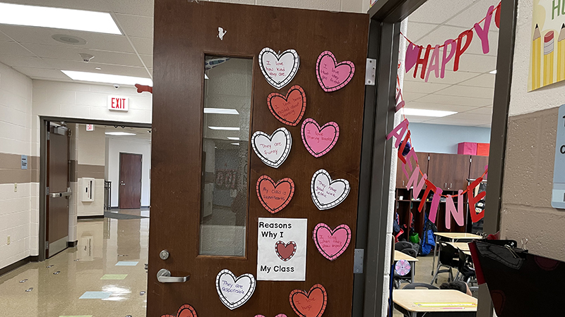 a classroom door decorated with hearts and messages from the teacher.