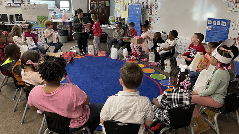 A kindergarten class gets help from their teacher to pass out Valentines.