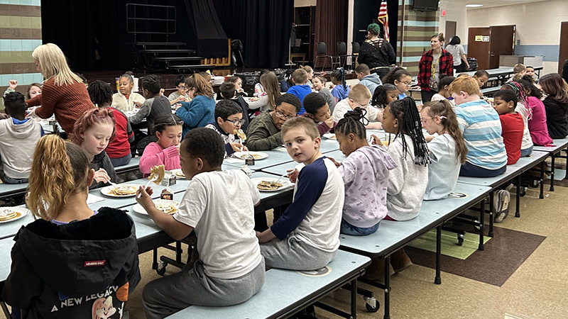 Students enjoying visiting together as they eat their pancakes.