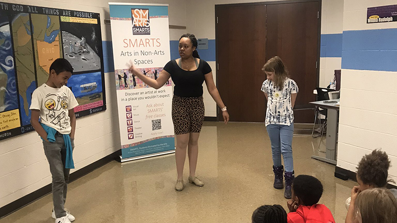 Student volunteers demstrate a dance for their classmates.