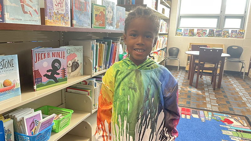 A kindergarten student wears a rainbow colored hoodie to celebrate color day