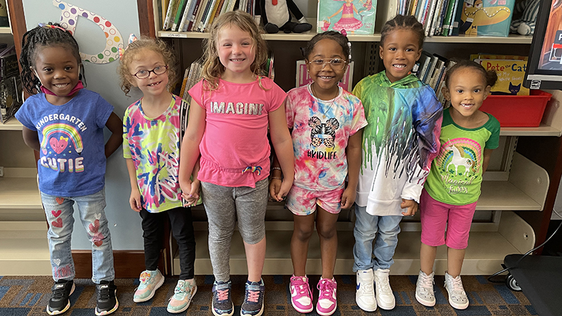 kindergarten students show off their rainbow colors while in the library.