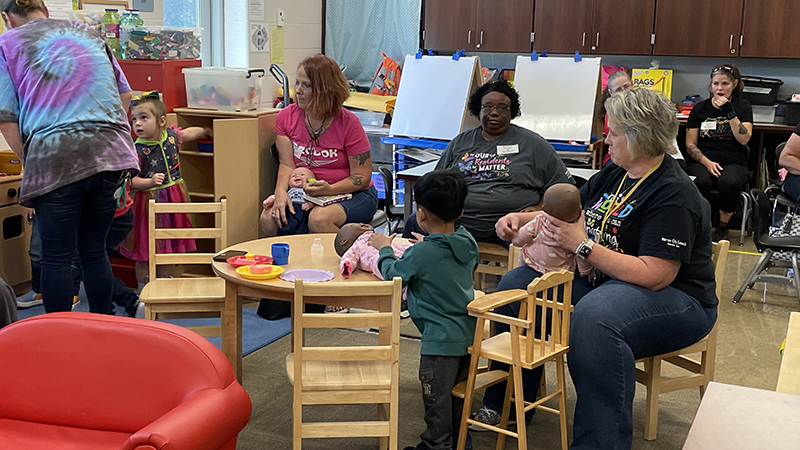 preschoolers and their guests play in the house center.