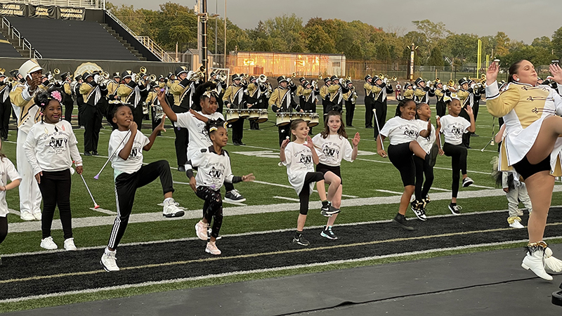 Mini majorettes perform the raider cheer with the band.