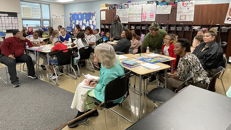 Students and guests listen as Mrs. Ulrich explains a math activity.