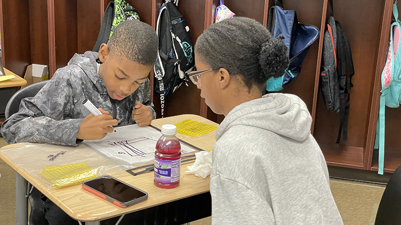 A student works on a math problem with the help of his guest.