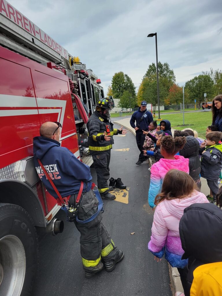 A fireman shows preschoolers his full safety gear.