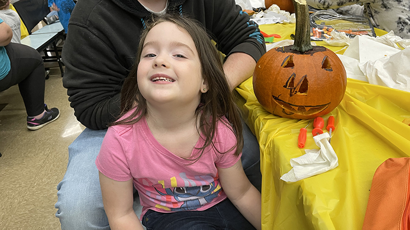 A student proudly shows her finished pumpkin.