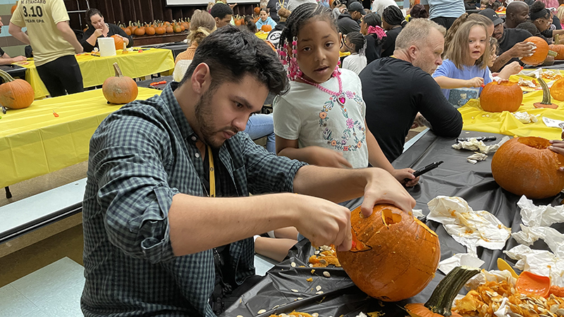 Mr. Girard helps a student carve their pumpkin.