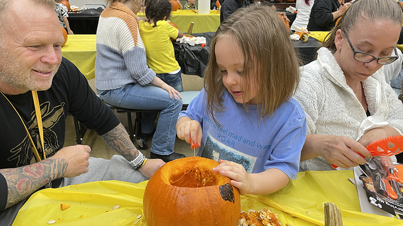 A student carves her pumpkin.