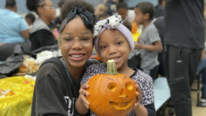 A kindergarten student and her sister show off their finished pumpkin.