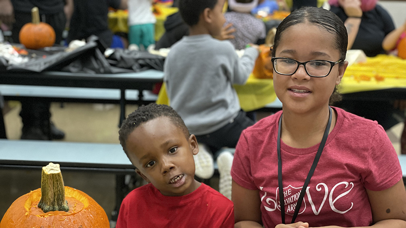 A student and middle school student show their finished pumpkin.