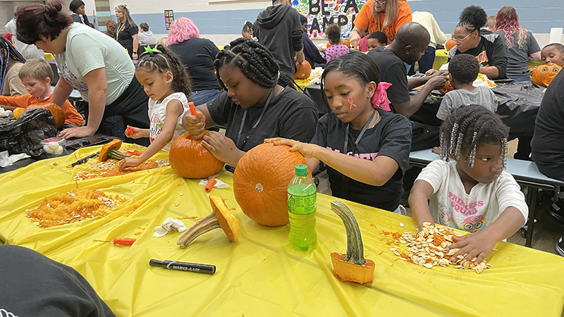 Student council members work to help kindergarteners on their pumpkin.