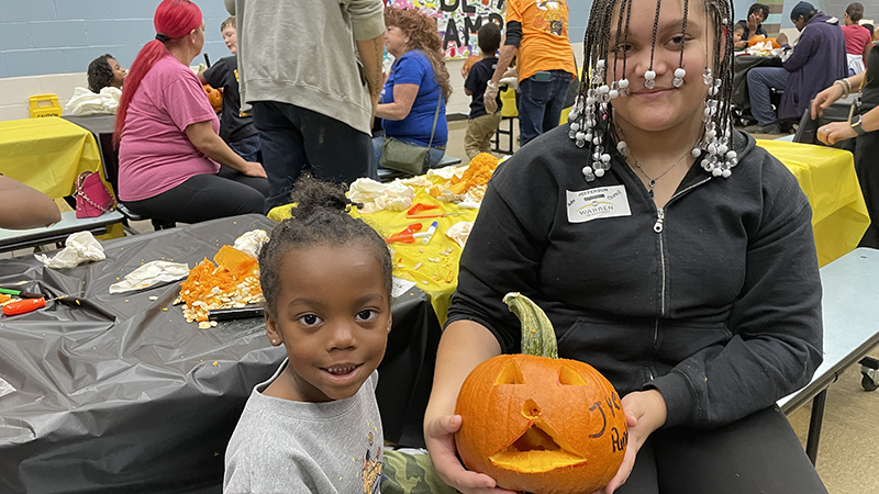 A kindergartener and his student council helper show off their finished work.