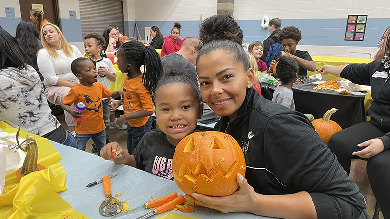 A student and their guest show off an amazing pumpkin.