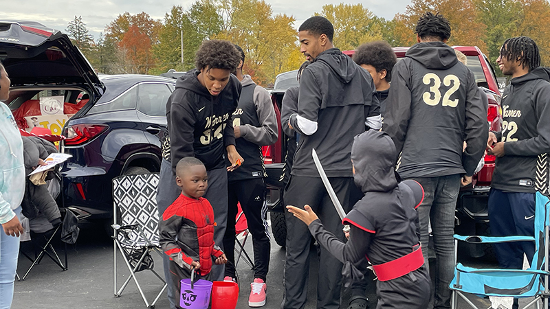 Harding football players pass out candy at trunk or treat.