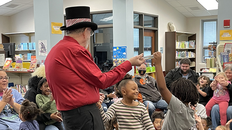 Students smile as they help with a magic trick.