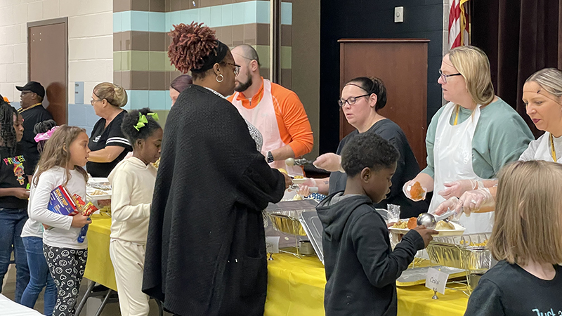 Ms. Betts and her class stand in line to get their meal.