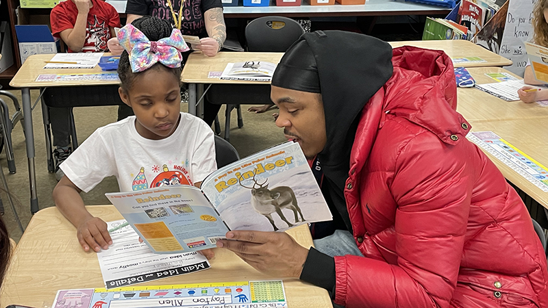 A first grader and her guest read a story together.