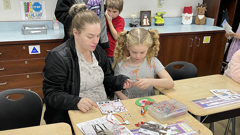 A student and her guest work on a craft.