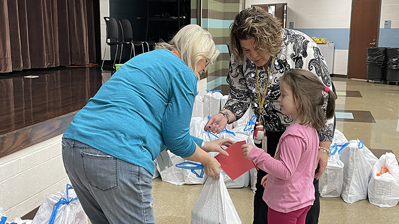 A student gives a thank you card to a volunteer from Believers Church.