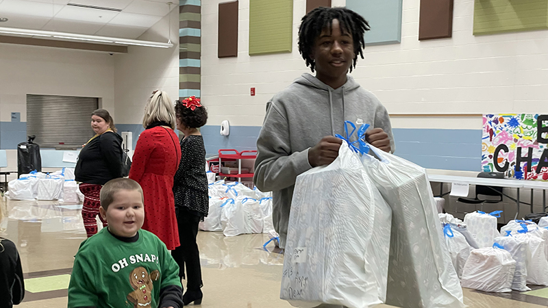 Student helper carries a student's bag of gifts.