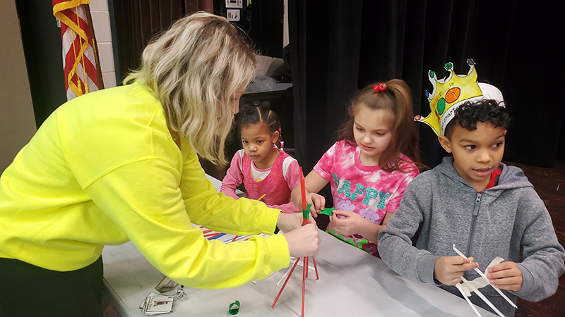 Mrs. Lasher helps build the group's tower for the challenge.