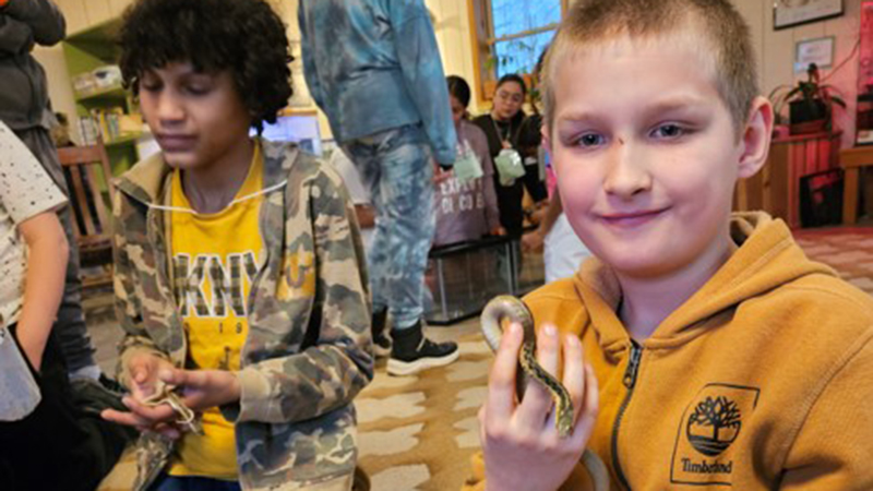 Two fifth graders hold the gardener snakes in the animal learning center.
