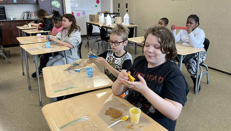 Students stretch and mold their slime.