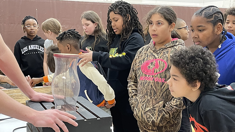 Students watch electrical experiments in action.