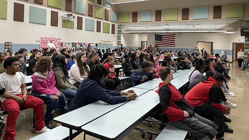 Middle school students listen intently to the speaker.