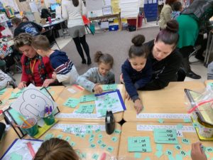 1st grade students playing a word game with parents at desks