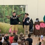 Two teachers in the front of an auditorium teaching students in costume