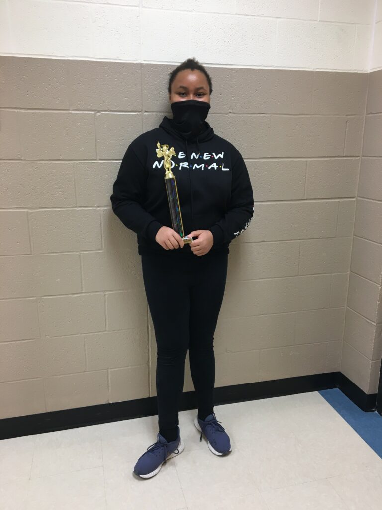 Middle school girl holding a spelling bee trophy