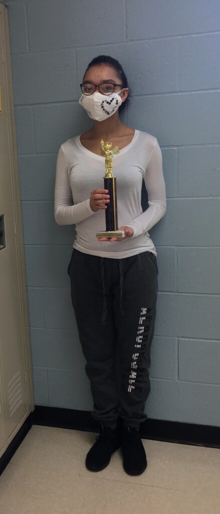 Middle school student holding a spelling bee trophy