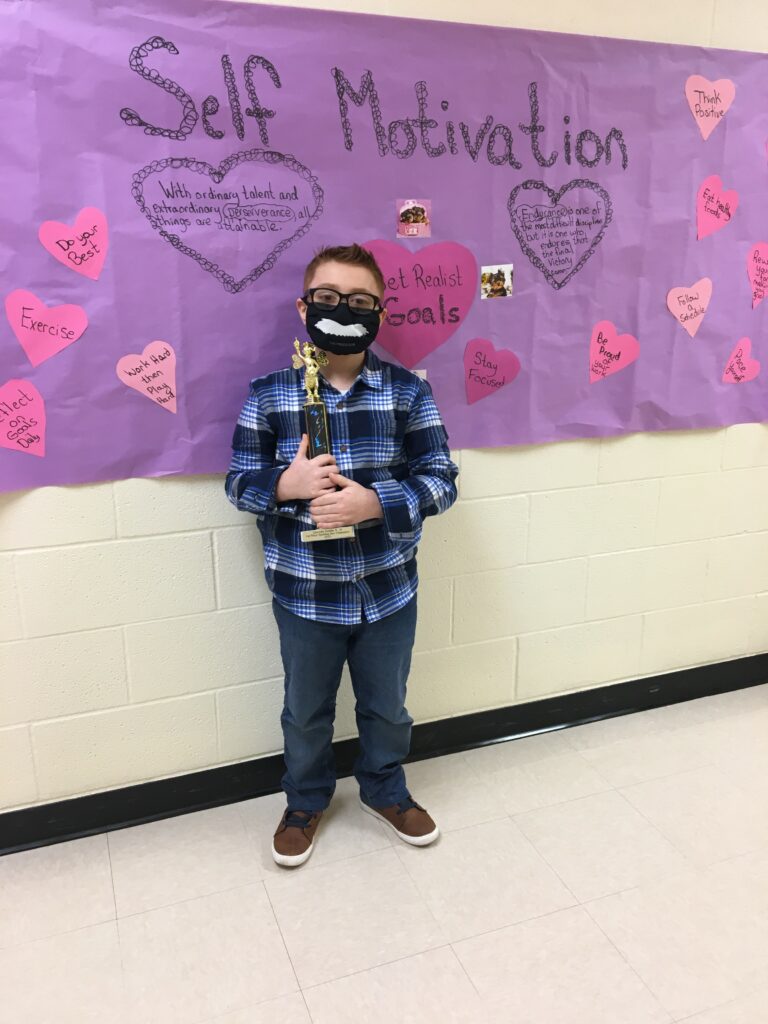 elementary school boy standing in front of a bulletin board