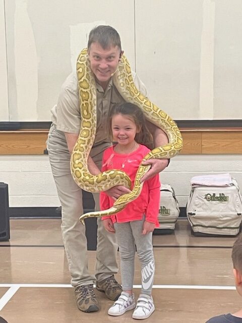man with a girl and a snake hugging around her neck