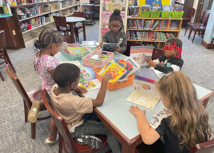 A group of students look at several library books.