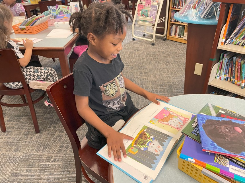 A student practices book care techniques while looking at her library book.