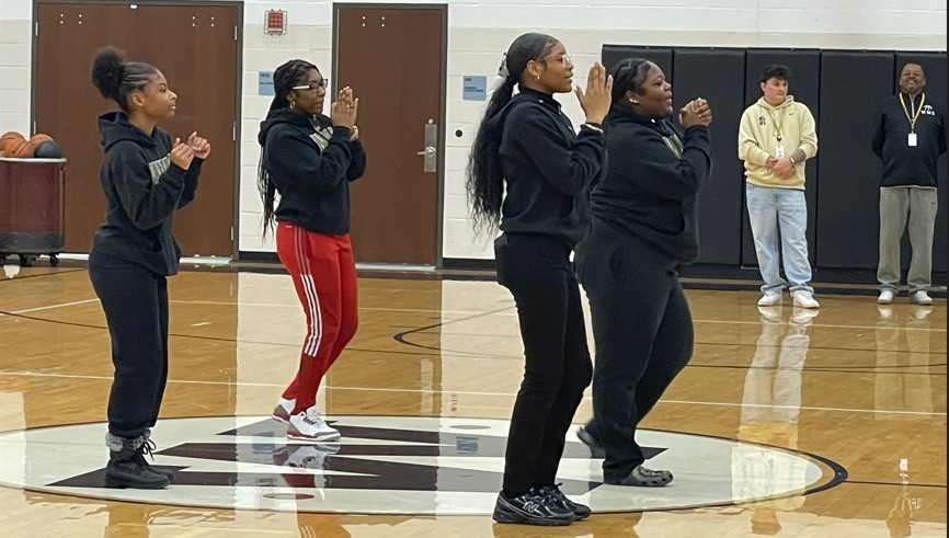Cheerleaders showing the students one of their cheers