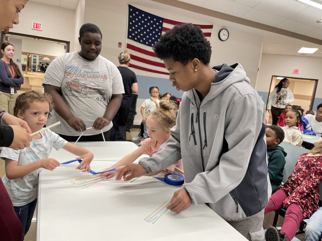 An eighth grader helps younger students with the challenge.