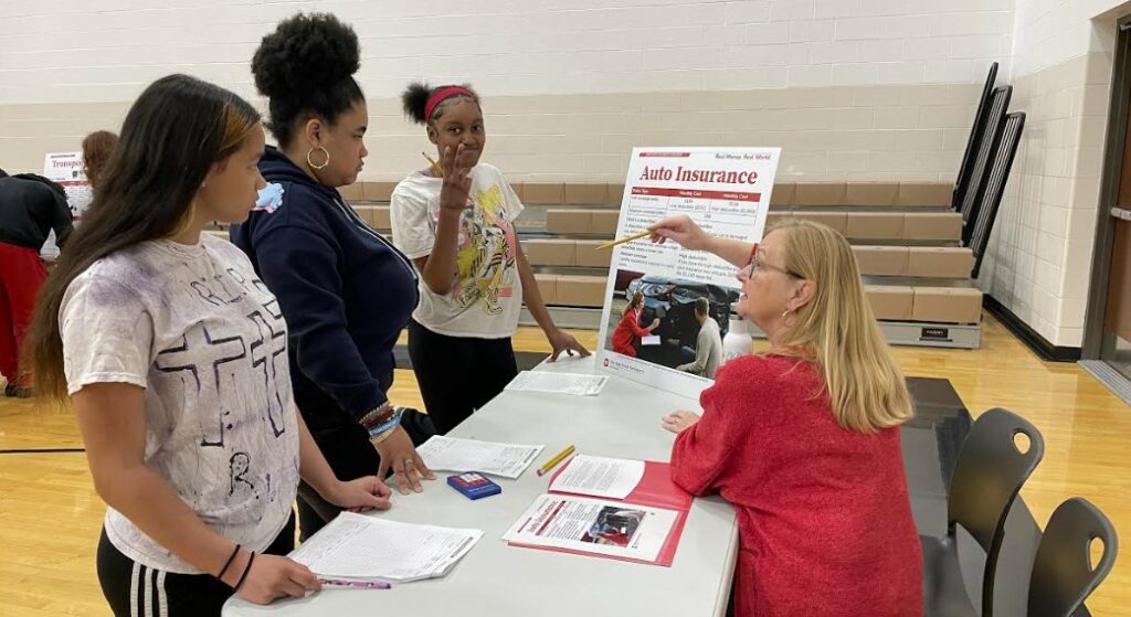 Students listen as a representative explains budgeting for auto insurance