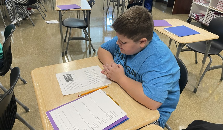 A middle school student reads a passage before answering the questions.