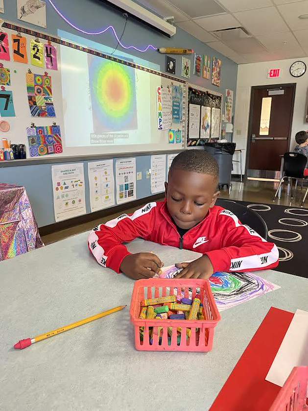 A first grade student works hard on his artwork