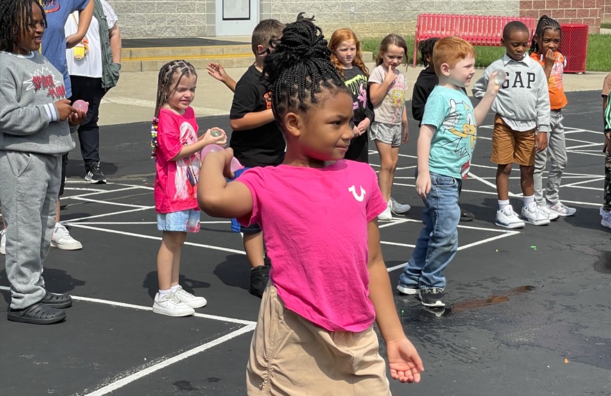 A first grader throws her water balloon at Ms. Prater