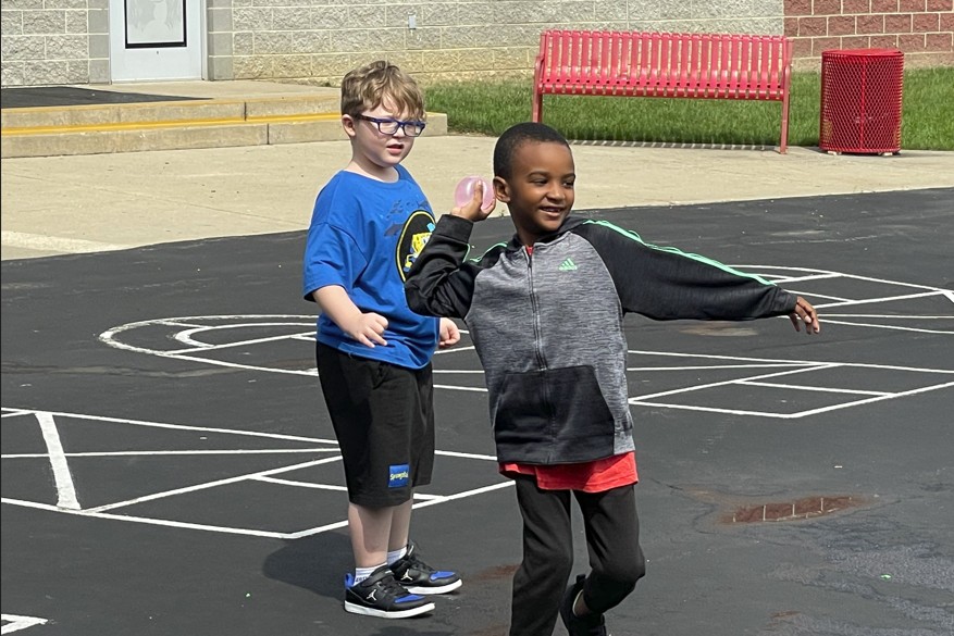 A first grader throwing his water balloon at Mrs. Tamburro